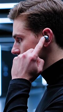 young white man wearing earbuds controls audio with fingertip in futuristic bluelit corridor, closeup profile shot, turtleneck styling, smart wearable demo, sleek design details, neon