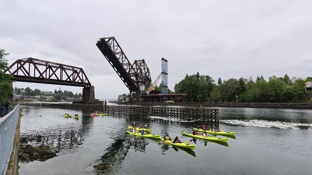 Kayaks paddling under a raised bascule bridge in Washington