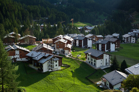 Beautiful alpine village with traditional wooden chalets on green hills in Zermatt Switzerland
