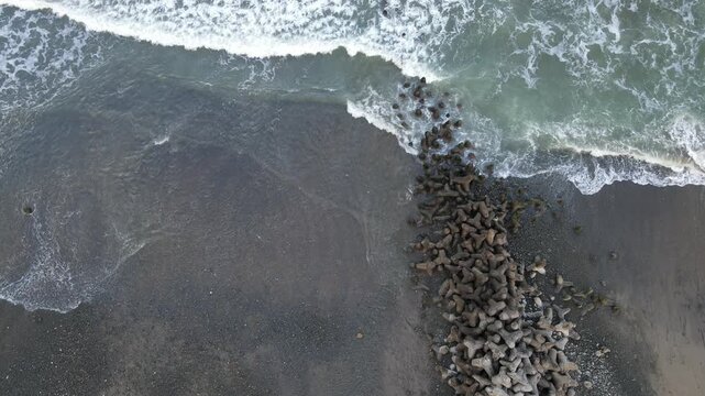 Aerial View of Crashing Waves Against Breakwater at Scenic Watubale Beach, Kebumen, Indonesia