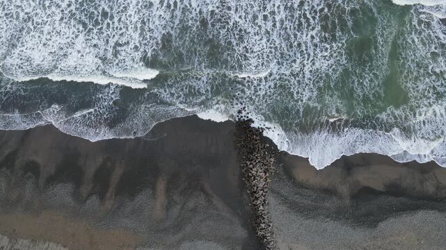 Aerial View of Crashing Waves Against Breakwater at Scenic Watubale Beach, Kebumen, Indonesia