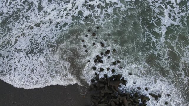 Aerial View of Crashing Waves Against Breakwater at Scenic Watubale Beach, Kebumen, Indonesia
