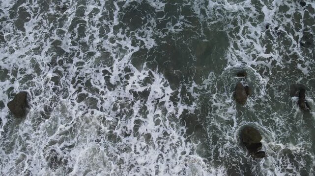 Aerial View of Crashing Waves at Scenic Watubale Beach at Sunset, Kebumen, Indonesia. Drone view of powerful ocean waves crashing along the rugged shoreline