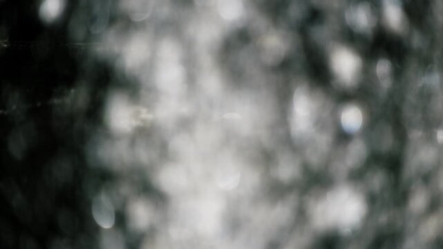 勢いよく飛沫を滴らせ落ちる噴水の水しぶき　キラキラ太陽の光を反射して輝く丸ボケ　夏・日本の季節・夏休み・水遊びの風景　