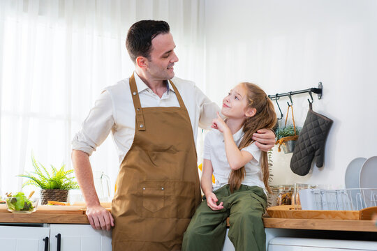 Father and daughter wearing aprons spending time together in the kitchen, Happy family moment with dad and daughter cooking in the kitchen, Father talking with his little daughter in home kitchen
