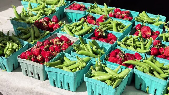 Fresh strawberries and green beans in blue crates at a farmers market