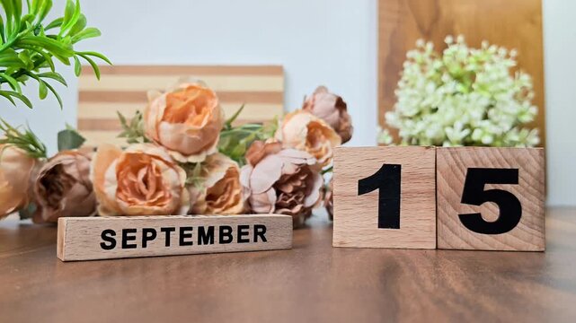 Hand placing wooden calendar blocks showing september 15 on a wooden table