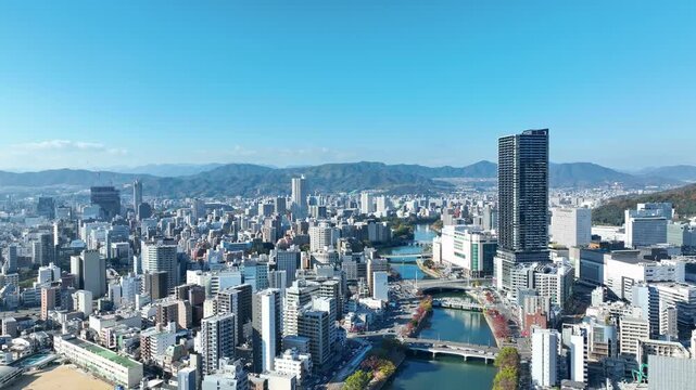 都市、社会、ドローン、空撮、河川、交通、建設、青空、環境、自然、防災、天気、晴れ、昼間、橋、インフラ、行政、物流、ロジスティクス、産業、ビジネス、開発、発展、ビル、紅葉、コピースペース、河川敷、堤防、マンション、不動産、地方、広島、日本、俯瞰、展望、パノラマ、地平線、山林、山地、住宅、経済、暮らし、経営、スカイライン、水運、タワマン、都会、風景、景色