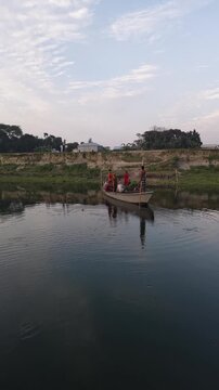 Rural river scene with small boat carrying people and goods at sunset with calm water reflections