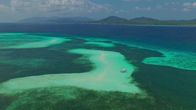 Aerial drone orbit shot flying right to left around the white sandbar of Bugsuk Island near Punta Sebaring in Balabac Palawan Philippines over shallow turquoise water and coral reefs