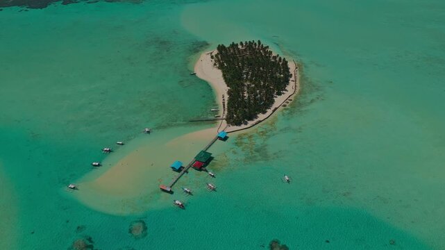Aerial drone slow high altitude clockwise orbit shot above Onuk Island in Balabac Palawan Philippines revealing the entire tropical island white sand beaches and surrounding turquoise coral reef