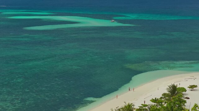 Aerial drone tracking shot flying right to left along the coast of Bugsuk Island near Punta Sebaring in Balabac Palawan Philippines facing the long white sandbar and shallow turquoise waters