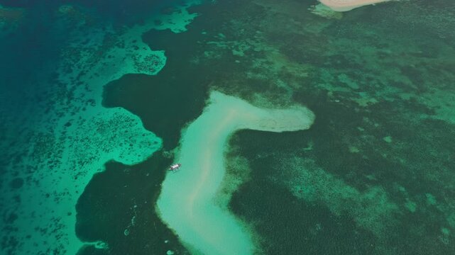 High angle 45 degree aerial flight over Candaman Sandbar in Balabac, Palawan, Philippines. Drone tracks forward over pristine white sand ridge, starfish habitat, and clear turquoise sea.