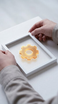 Framed gear symbol represents customer value proposition cvp concept with hands holding white frame on light background