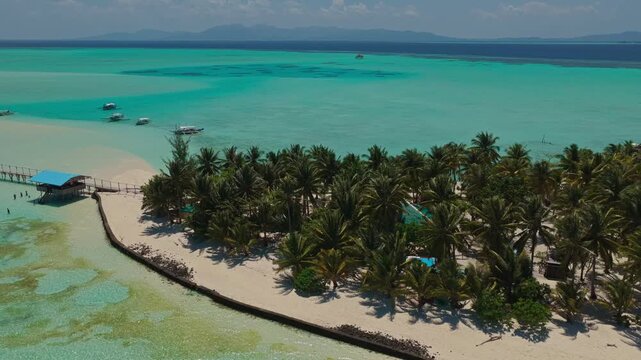 Aerial drone flight flying backwards along the island perimeter of Onuk Island, Balabac, Philippines. Reverse tracking shot reveals tropical white sandbar, reef edge, and turquoise ocean.