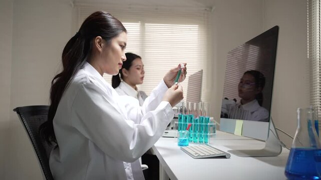 Focused young Asian woman scientist conducting chemical research in laboratory using pipette to test liquid sample tube