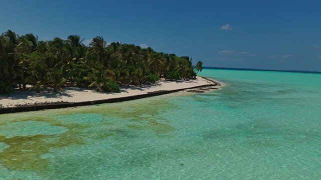 Aerial tracking orbit of Onuk Island from the sea, Balabac, Palawan, Philippines. Drone flies counter-clockwise over turquoise ocean facing remote tropical paradise with stilt houses.