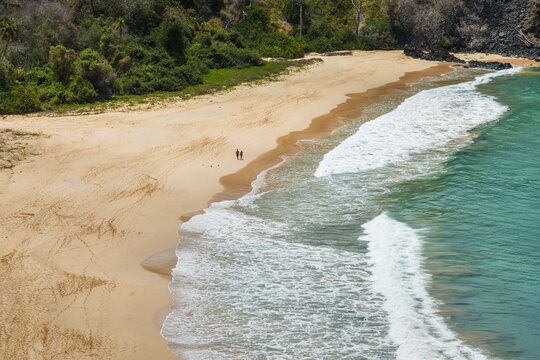 Aerial view of a turquoise beach and cove with couple walking, Fernando de Noronha, Pernambuco, Brazil