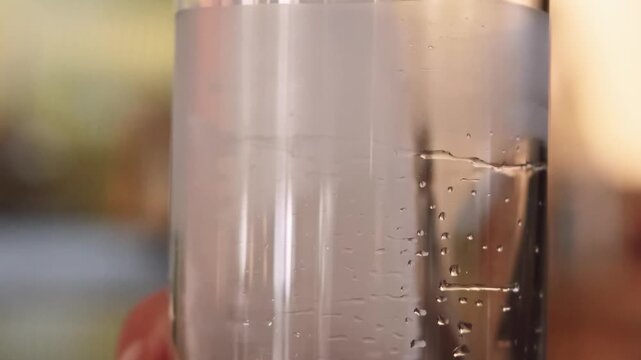 Preparing beverage. Cocktail making. Barkeeper hand rotating ice cube in tall glass with water drops. Cooling for refreshing drink.