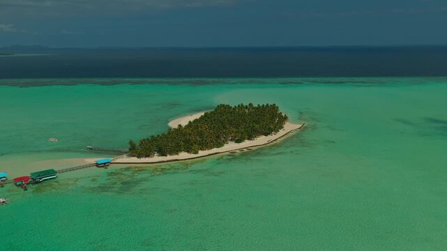 Long distance aerial drone orbit shot moving counterclockwise around Onuk Island in Balabac Palawan Philippines during early morning sunrise with golden hour light over serene ocean water