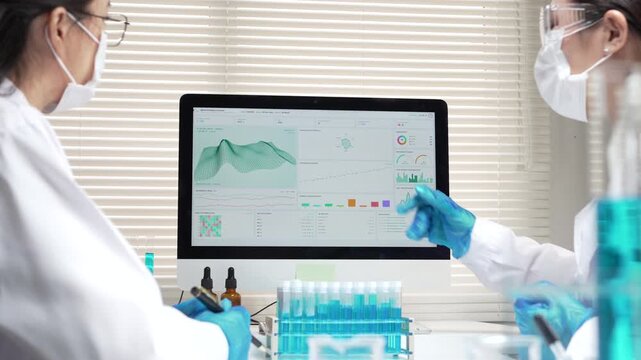 Focused scientist team analyzing medical laboratory data chart on computer screen wearing protective glove with test tube