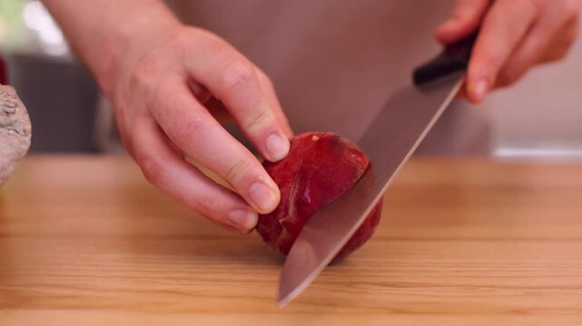 Natural nectarine. Fruit slicing. Unrecognizable experienced man chef hands using knife on wooden board cooking dessert at workplace.