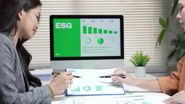 Focused businesswoman during professional esg document discussion inside office reviewing green report on computer screen chart