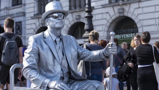 Silver Living Statue Street Performer in Metallic Suit Posing as a Mime in Public Square