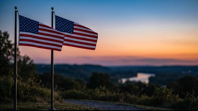 Two American flags waving at sunset overlooking a scenic valley and river