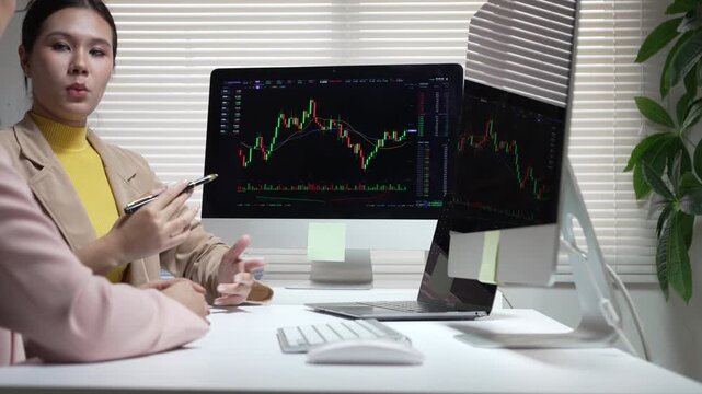 Professional woman investor and trader at office desk analyzing stock market chart on computer screen during finance meeting
