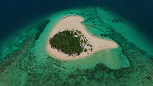 Aerial vertical ascent looking forward at Patawan Island, Balabac, Palawan, Philippines. Straight up climbing drone shot reveals tropical beach and ocean horizon.