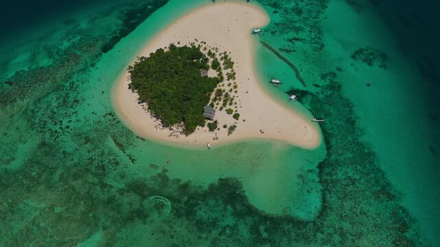 High altitude aerial backward flight with gimbal tilt up over Patawan Island, Balabac, Philippines. Reverse tracking drone shot reveals tropical reef and ocean horizon.