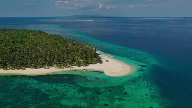 Aerial vertical descent looking at Tangkahan Island from open sea, Balabac, Palawan, Philippines. Drone drops down over deep ocean facing remote tropical hook sandbar.