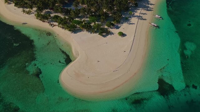 Aerial drone flight flying backwards to reveal Tangkahan Island, Balabac, Palawan, Philippines. Reverse tracking pull-away shot showcases tropical white sandbar, palm trees, and turquoise reef.