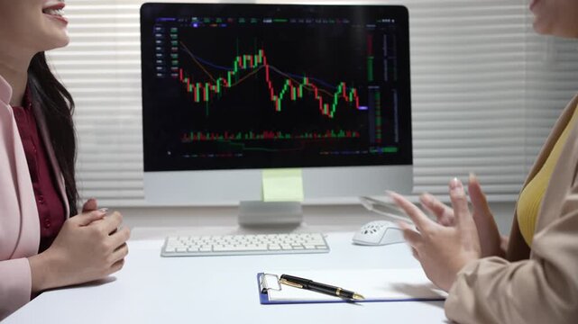 Smiling businesswoman analyzes stock chart during finance meeting, finalizing deal with happy investor in office discussion
