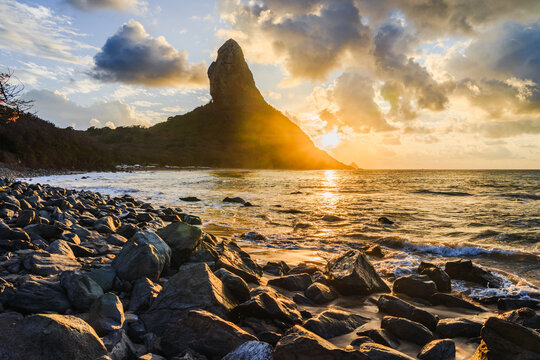 Sunset behind Morro do Pico over a rocky shore, Fernando de Noronha, Pernambuco, Brazil
