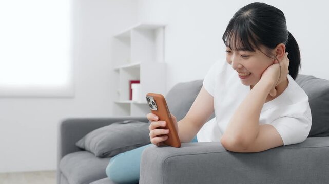リビングでスマホを使う10代女性