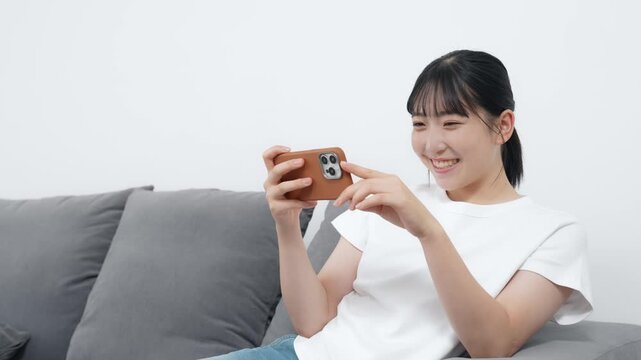 リビングでスマホを使う10代女性