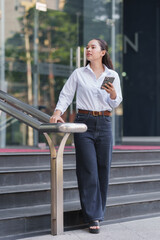 Fototapeta premium Woman standing on urban staircase using phone