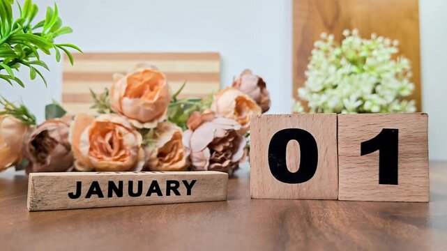 Hand placing wooden calendar blocks showing january 1 on a wooden table