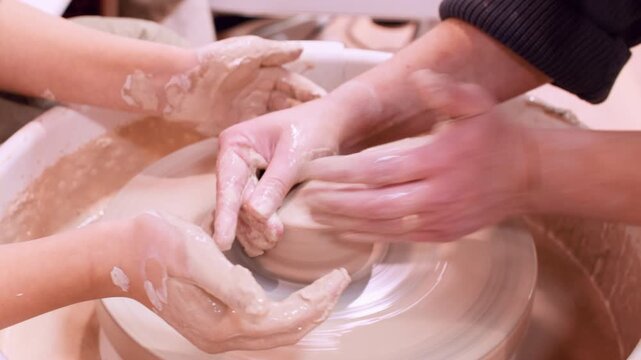 Talented craft. Creative learning. Unrecognizable woman master hands teaching girls pottery ceramic in class using electric professional wheel.