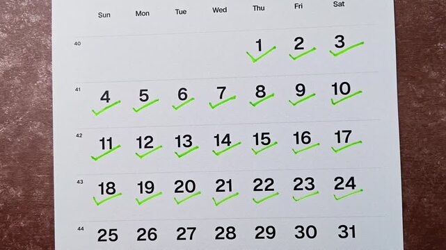 Hand putting green checkmark on calendar date 24. Goal achievement, success and task completion concept