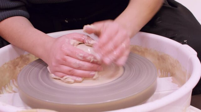 Pottery hobby. Hands clay forming. Unrecognizable professional woman master shaping raw for crockery craft using wheel in ceramic workshop.