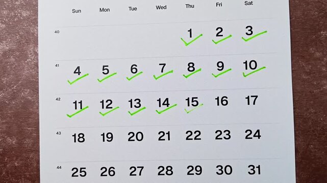 Hand putting green checkmark on calendar date 15. Goal achievement, success and task completion concept