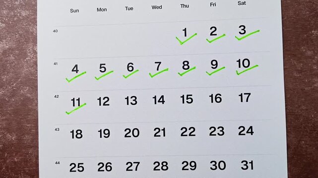 Hand putting green checkmark on calendar date 11. Goal achievement, success and task completion concept