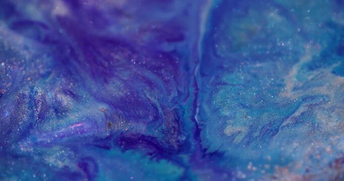 Acrylic spill. Shiny liquid texture. Purple blue particles liquid explosion on sparkling paint defocused color abstract background.