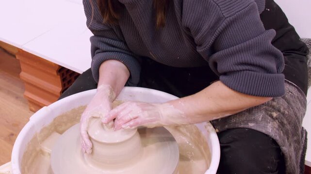 Pottery occupation. Making crockery. Unrecognizable female artisan hands forming raw clay using wheel for professional manufacturing.