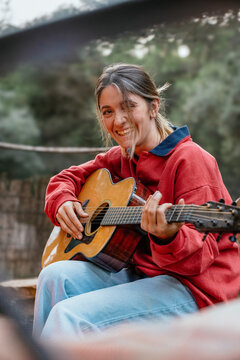 Woman smiling playing acoustic guitar outdoors