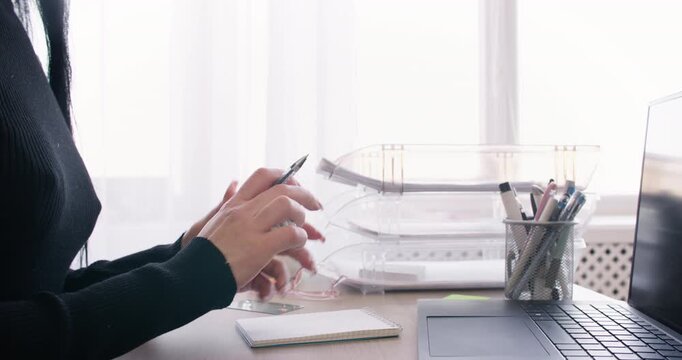 Office paperwork. Business lifestyle. Unrecognizable woman manager writing task in notebook at desk with laptop at workplace.