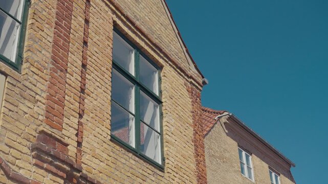 The facade of a traditional brick house with classic windows in the old town of Haderslev, Denmark.
